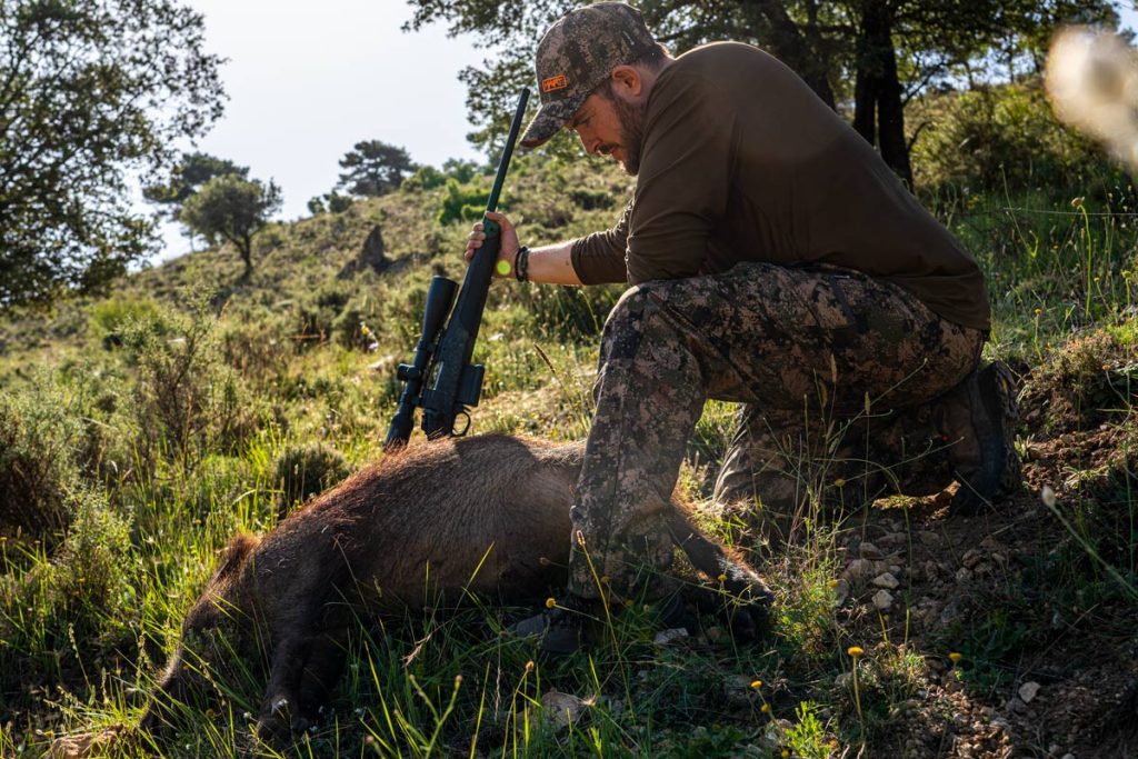 Un cazador con un jabalí abatido.